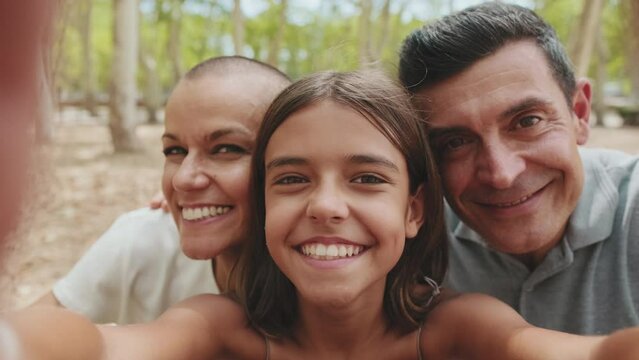 Close up, happy family taking selfie on mobile phone while sitting on park bench