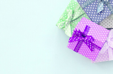 Pile of a small colored gift boxes with ribbons lies on a violet background. Minimalism flat lay top view.