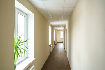 A long empty corridor in an office building. A new modern heating radiator on a white wall. Large...