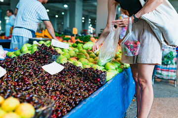 Woman picking up groceries at farmers market, buying healthy fresh fruits and vegetables