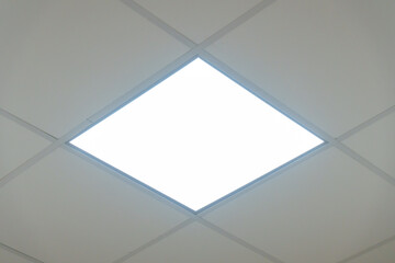 Square lamp on a white office ceiling. Interior design in the office. A fluorescent lamp on a modern suspended ceiling. - obrazy, fototapety, plakaty