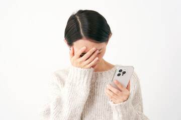 スマホを持って落ち込む中年女性　白背景