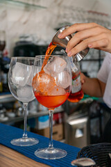 a bartender beginning to prepare a pair of aperol spritz cocktails 