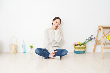 自宅でスマホで通話する中年女性　全身