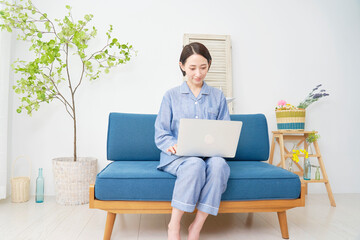 自宅でパジャマを着てノートパソコンを使う中年女性