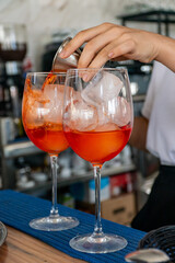 a bartender preparing a pair of Italian Aperol spritz cocktails at a mediterranean bar 