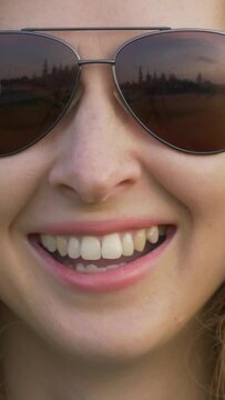 Young caucasian woman in sunglasses is smiling and laughing in park. Close up shot. Vertical Video