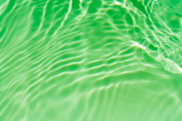 Green water waves on the surface ripples blurred. Defocus blurred transparent blue colored clear calm water surface texture with splash bubbles. Water waves with shining pattern texture background.