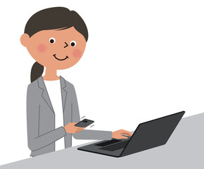 パソコン操作中にスマートフォンを確認するスーツの女性