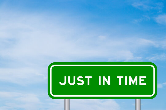 Green color transportation sign with word just in time on blue sky with white cloud background