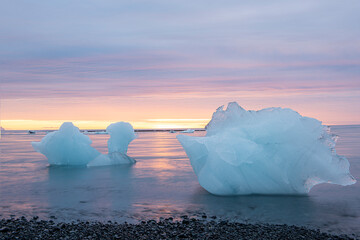  ice floes on black volcanic sand on the ocean shore at dawn. Jökulsárlón. glacier lagoon in...