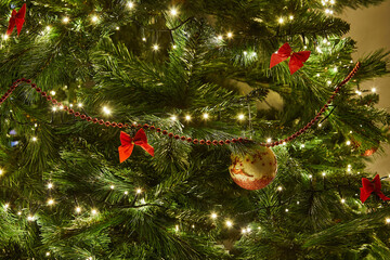 Close-Up of Christmas Tree with Ornaments and Garland with Lights