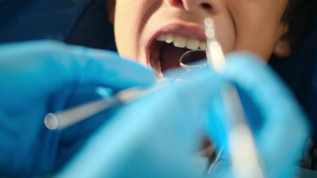 A kind female dentist examines a young patient for tooth decay, utilizing a dental probe and angled mirror.
