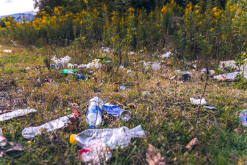 Close-up of plastic bottles, garbage in the grass. Illegal dumping of garbage in nature. Pollution...