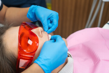 Close-up of a dentist in blue medical gloves flossing a patient's teeth. Professional dental...