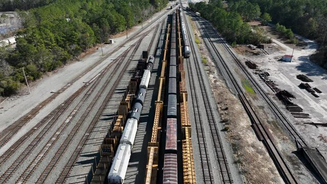 Aerial view of multiple train lines with assorted cargo containers and flatbeds on tracks, showcasing transport infrastructure.