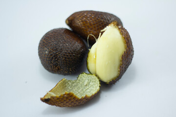 closeup of ripe snakefruit, half peeled and unpeeled at white background