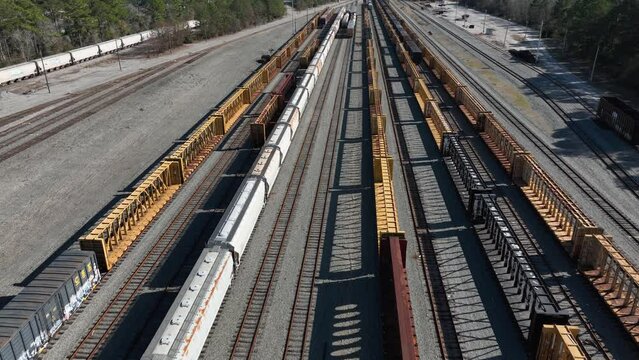 Aerial view of multiple train lines with assorted cargo containers and flatbeds on tracks, showcasing transport infrastructure.