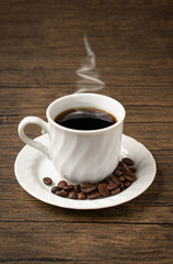Dark coffee in white mug on wooden table..