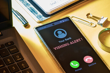 Smartphone screen showing phone call from bank with Vishing alert message. Phone call scam asking for bank details concept.