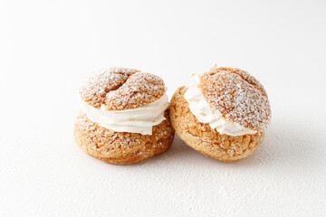 Cream puffs, pastry from choux covered  sugar powder on white background.