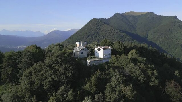 Aerial orbit with view of Maria Assunta Church over Mount Br&egrave;. Incredible landscape of mountains and forest. Drone shot over Mount Br&egrave;, Lugano.