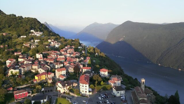 Aerial dolly at sunset with view of town of Br&egrave;, Lugano and Lake Lugano. Incredible landscape of mountains and lake. Drone shot over Mount Br&egrave;, Lugano. 