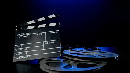 A clapper board and a reel of film roll on a wooden table . Film industry inventory in studio on...