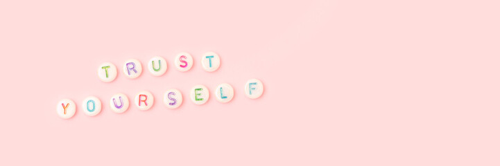 Trust yourself. Banner with quote made of beads with letters on a pink background.