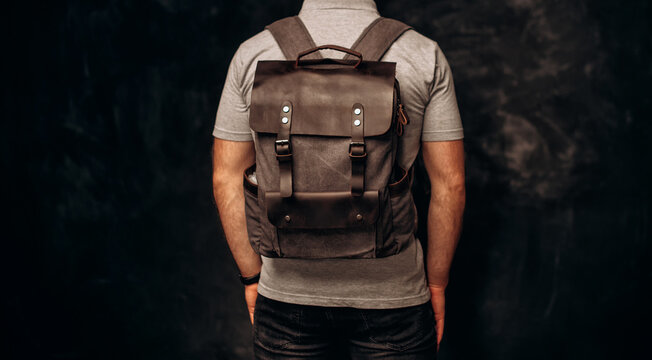 Man with stylish canvas backpack on dark background, back view. Close up