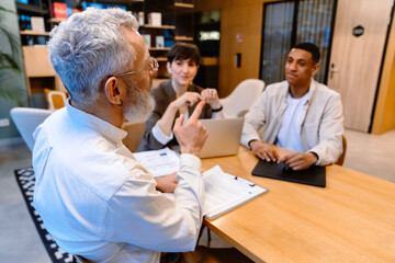 Group of mixed age colleagues discussing business issues during meeting in conference room