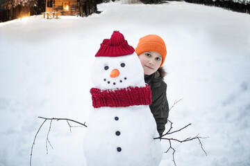 Cute kid teen boy building snowman outdoor nature winter and playing with him. Children winter...