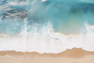 The image shows a large turquoise wave crashing onto a sandy beach