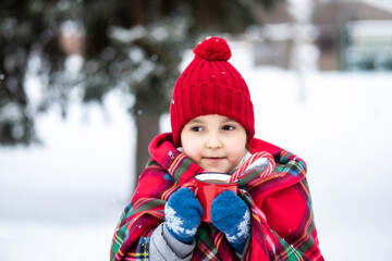 Happy child girl holding mug of hot cocoa, chocolate or tea. Children activity in winter day. Holiday vacation concept.
