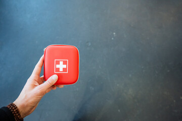 First aid kit in man's hand on grey background, personal safety concept.