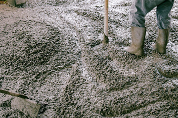 A construction worker pouring wet concrete at the floor construction site