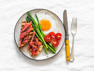 Breakfast, brunch plate - fried egg, asparagus, salmon sandwich on a light background, top view