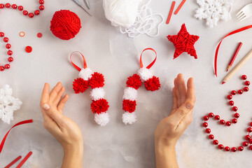 Making pom-poms from red and white threads. Ideas of Christmas decoration diy with kids. Candies...
