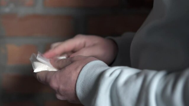 A drug dealer holds a bag of cocaine in his hand. Heroin drug addiction concept.