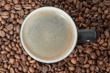 A cup of coffee on the background of roasted coffee beans. Coffee background with espresso.