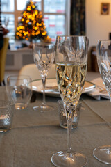 New year dinner served with champagne cava or prosecco wine in crystal glasses on table with christmas tree and garland lights on background