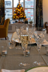 New year dinner served with champagne cava or prosecco wine in crystal glasses on table with christmas tree and garland lights on background