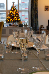 New year dinner served with champagne cava or prosecco wine in crystal glasses on table with christmas tree and garland lights on background