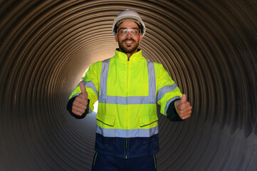 Smart engineer with safety suit holding walkie-talkie inspecting large power system pipeline.	
