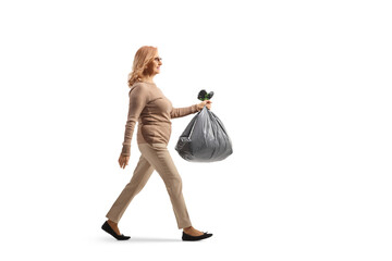 Full length profile shot of a middle aged woman carrying a plastic waste bag