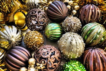 Fototapeta na wymiar New Year's Christmas balls, tinsel and decorations close up. A lot of decoration of golden, brown, yellow, green. Striped Christmas balls. Festive beautiful colorful background. Home holidays design.