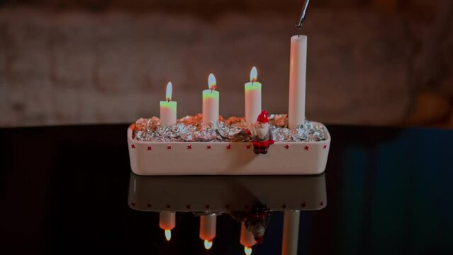 Close-up view of lighting the fourth candle on the traditional Advent candle holder as part of the Christmas celebration. Sweden.