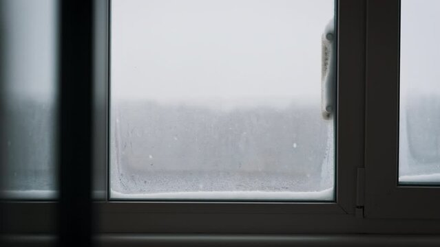 Winter view from a window with thermometer outside. Winter landscape through the window in the house. Beautiful winter weather with falling snow outside on winter day. Snow stuck on the thermometer.
