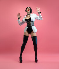 sexy woman with glasses, in a BDSM mistress costume in stockings, posing sexually on a pink copy paste background