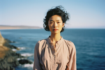 portrait headshot of a young asian/korean/japanese woman with long dark hair traveling in nature vacation lake summer blue sky portra magazine editorial film look